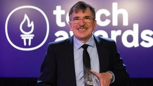 Jack Johnson standing with the TORCH Awards logo in the background holding his award.