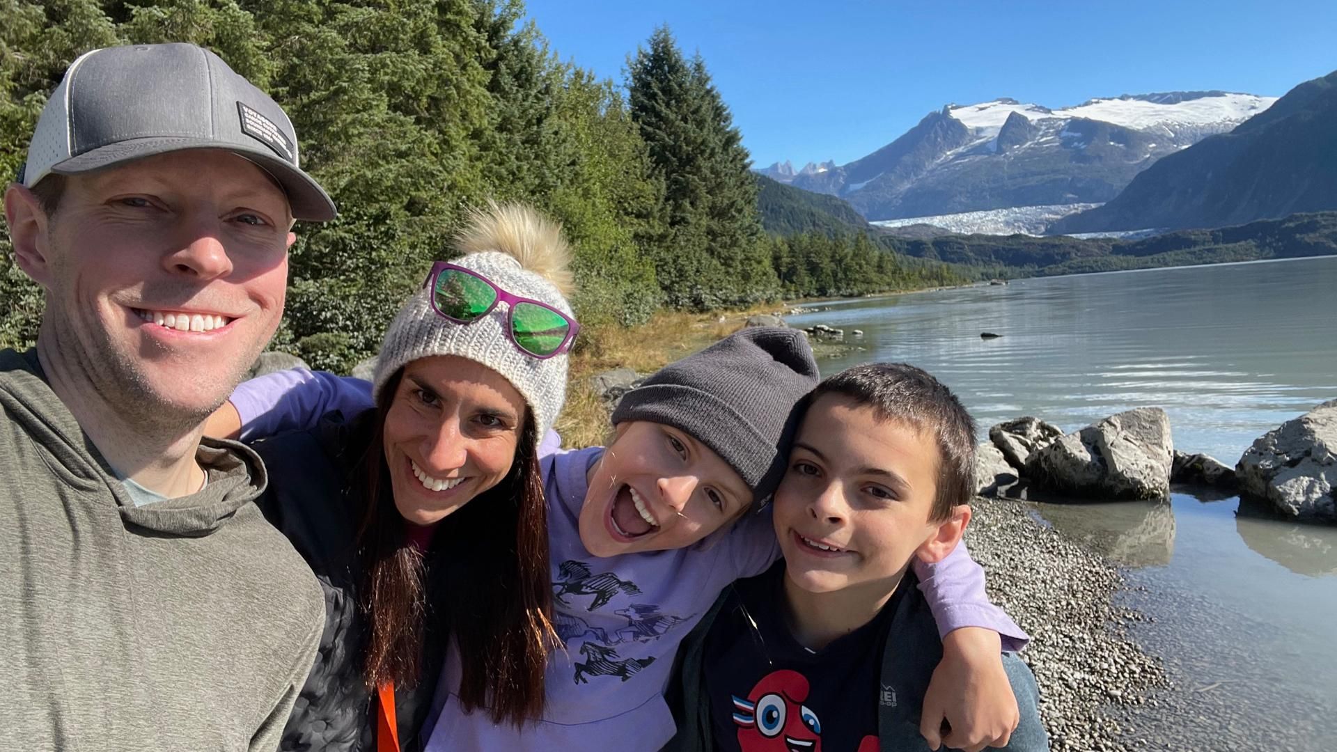 Dr. Sharff with her husband and two kids against trees, a pond, and mountains
