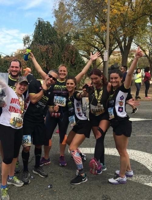 Kate and 6 friends in running gear celebrate with each other at mile 18 of the Boston marathon.