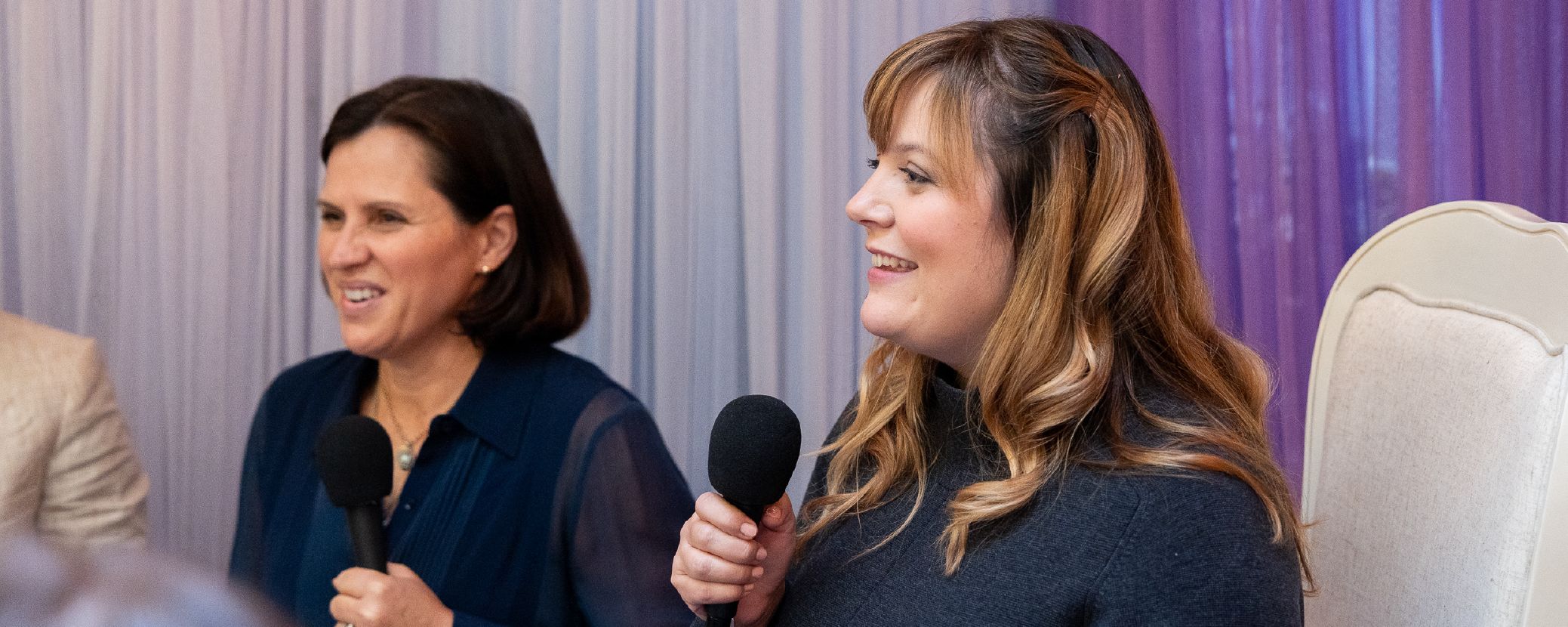 two women speak into microphones