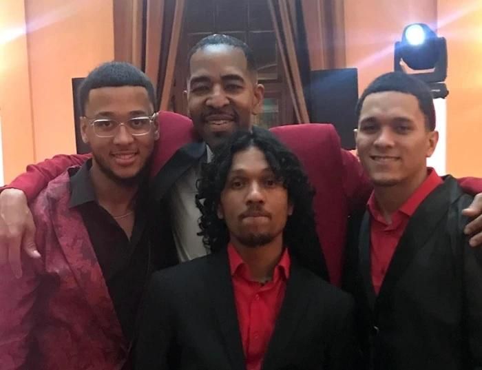 Phillip St. James stands with his arms around his three sons.