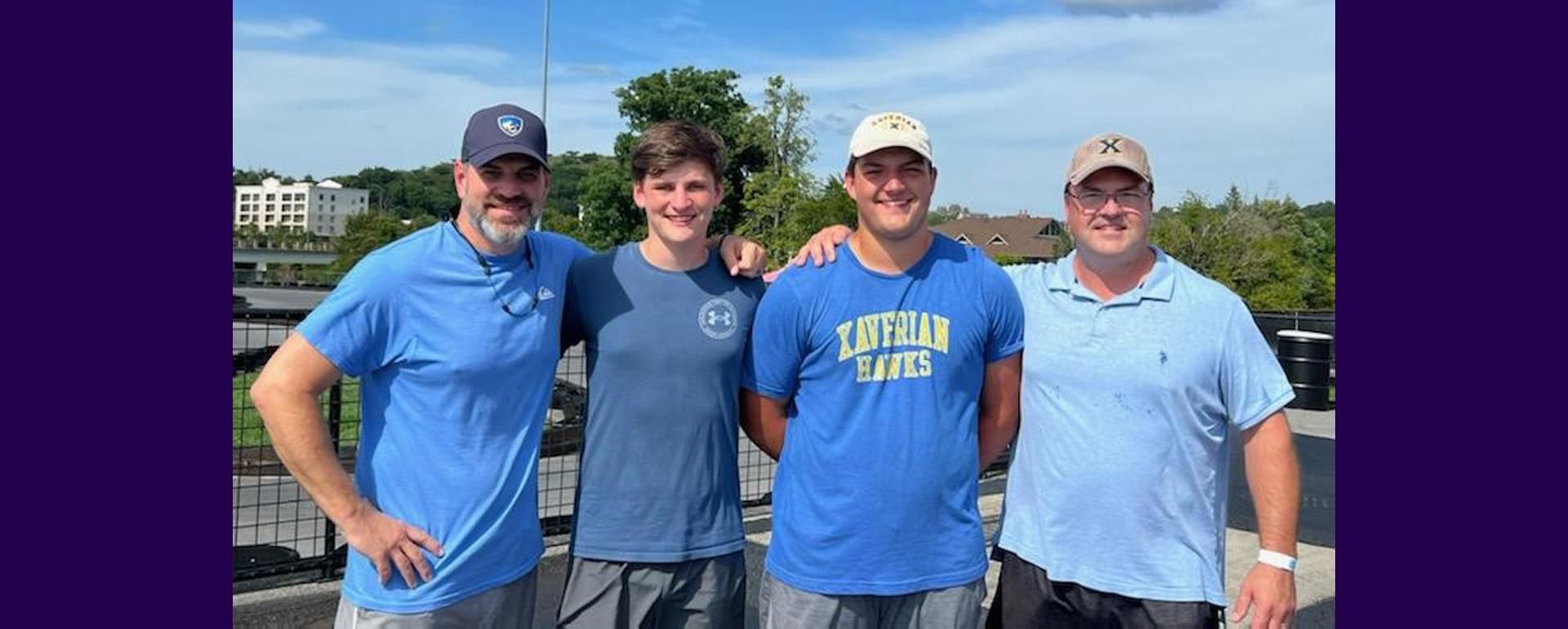 Friends Micheal and Steve stand with their sons Andrew and Jay between them.