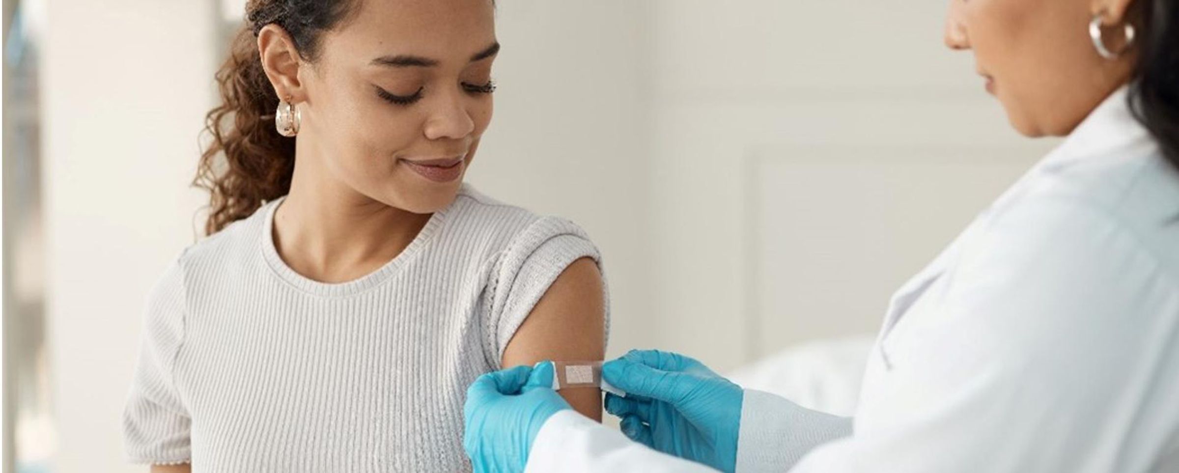 A female patient receives a bandage on her arm from a doctor after her flu shot.