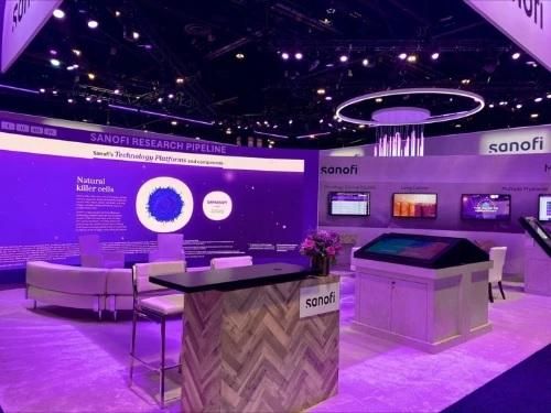 The Sanofi ASCO booth set up with tables and chairs and interactive displays about the companie's work in oncology.