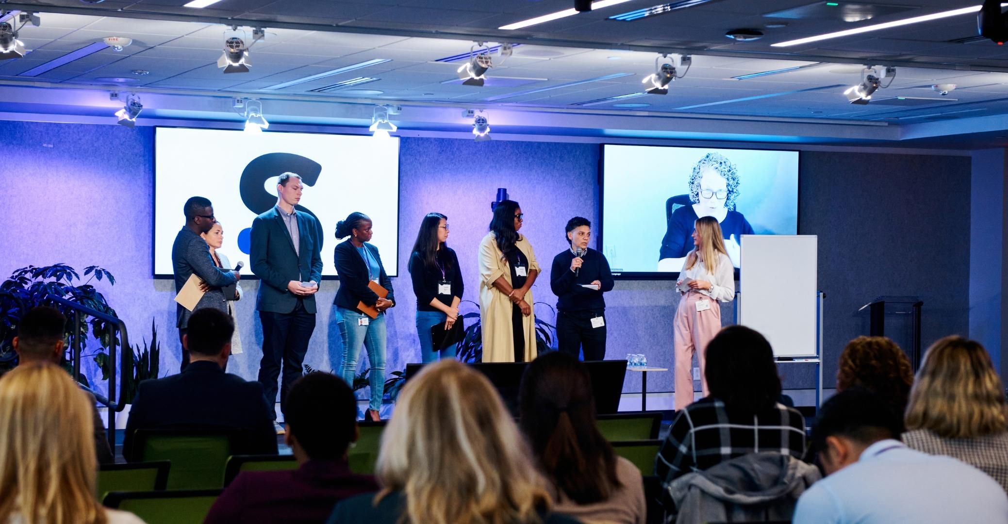 Participants of the TIE Summit standing on stage as they share insights from breakout group discussions