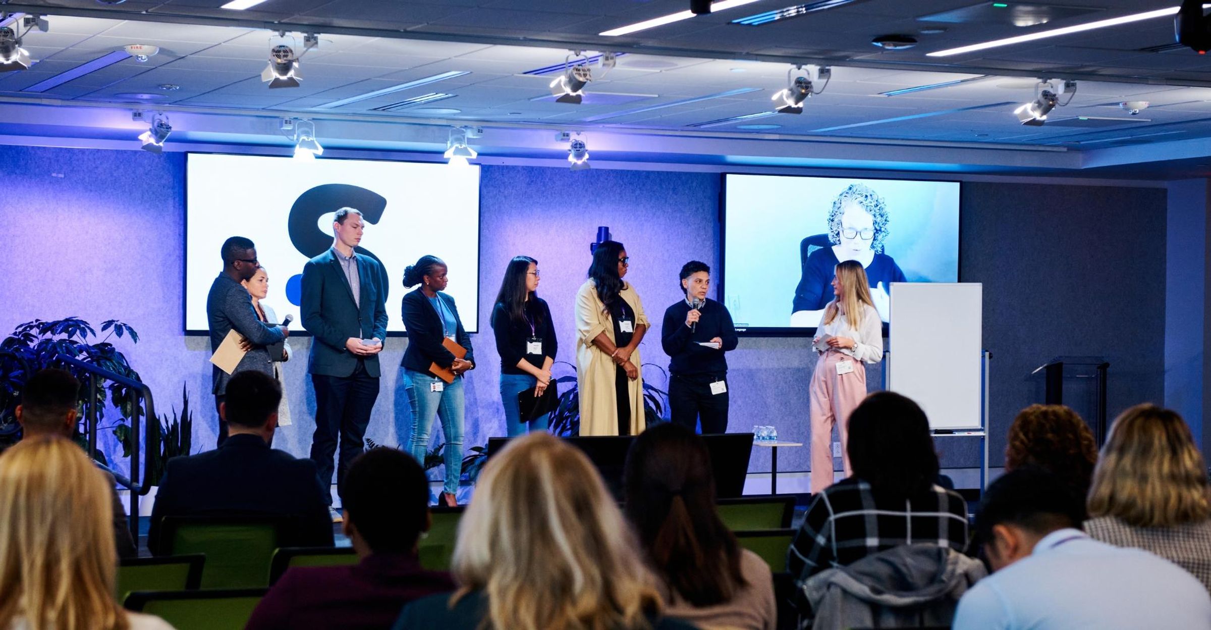 Participants of the TIE Summit standing on stage as they share insights from breakout group discussions