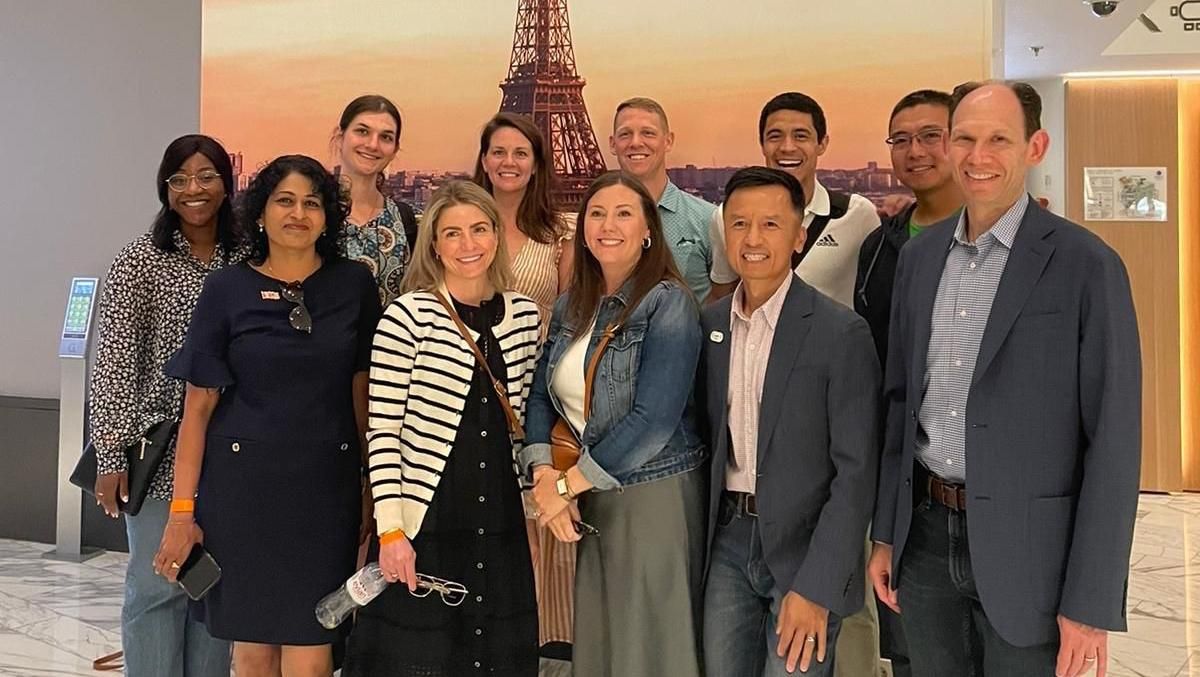 The North American Sanofi Cup Team stands in a group in front of a photo of the Eiffel tower.