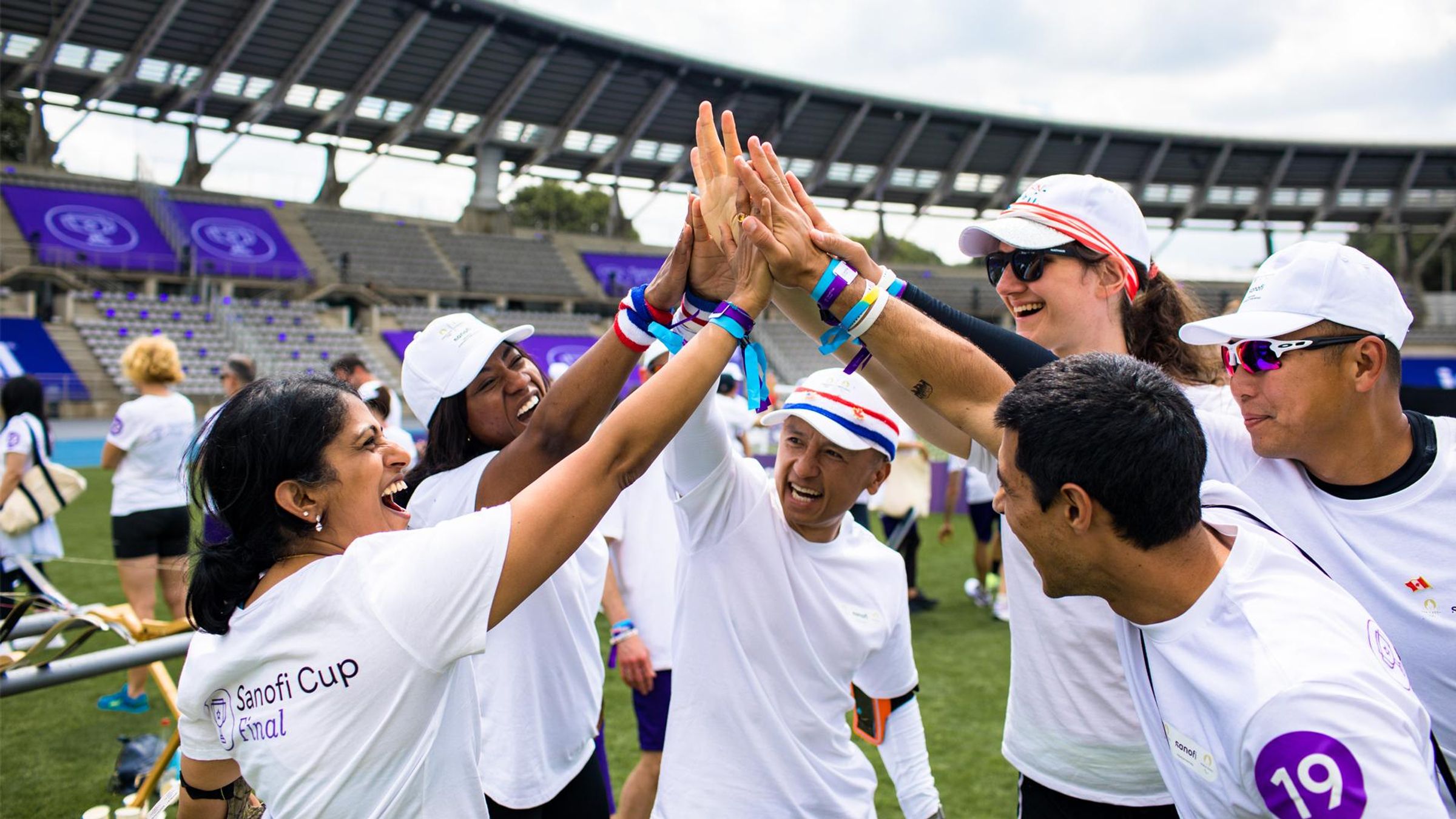 The North America Sanofi Cup team stands in a circle giving each other a group high five.