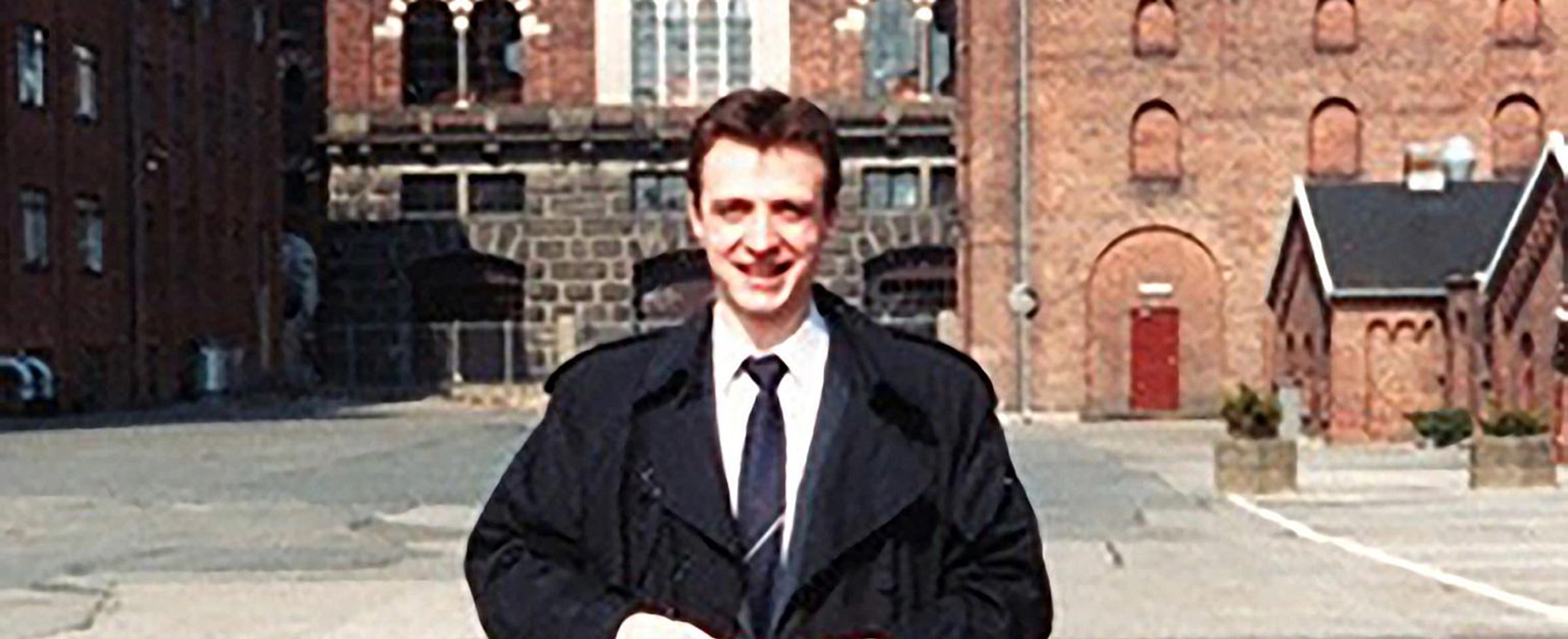 Dr. Vitali Pool smiles at the camera while standing against a backdrop of a european town.