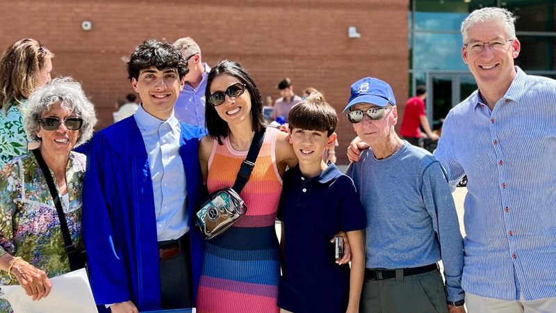 Lew standing arm in arm with five members of his family at his grandson’s graduation.