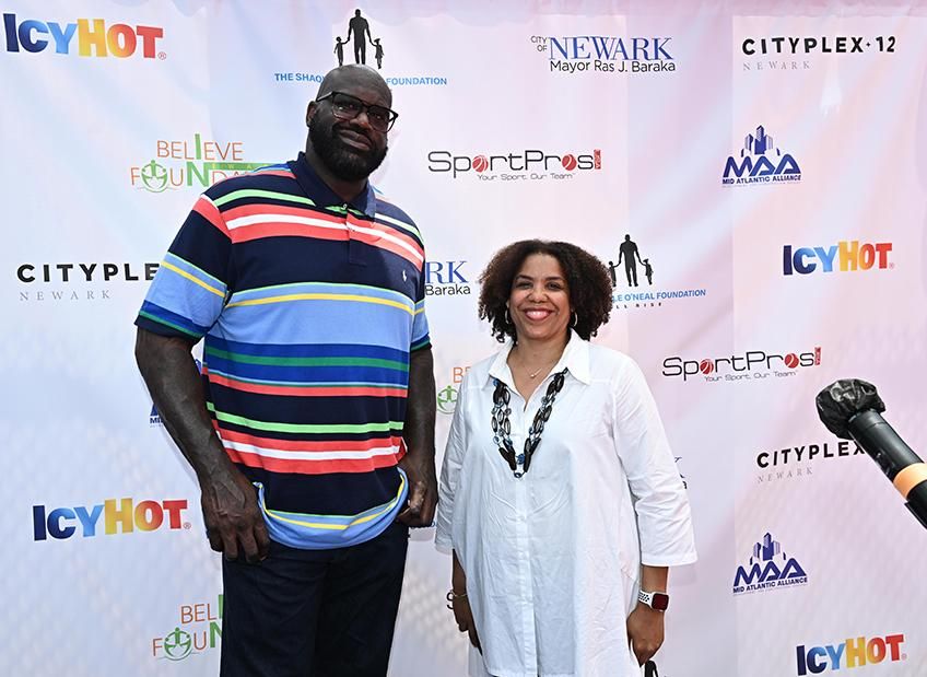 Shaquille O’Neal and Helene Pamon stand against a step and repat background at the Icy Hot® “Combaq Court” event in Newark, NJ.