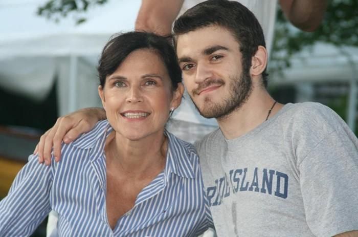 Jane Smith's son wraps his arm around his mother while both smile at the camera.