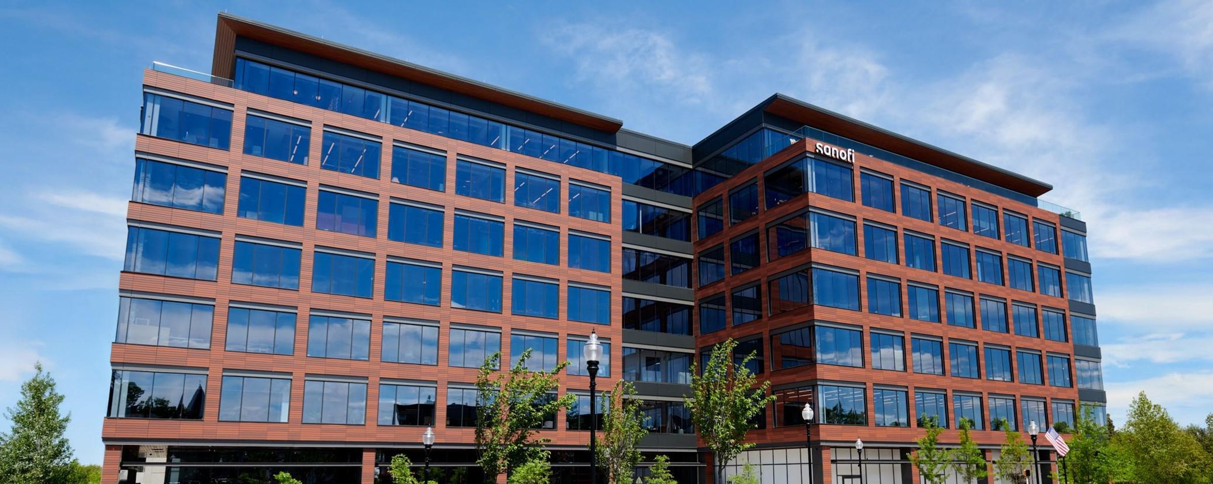 Six-floors of a seven-floor building are visible with a brown façade, a large number of floor to ceiling windows, and the Sanofi logo.