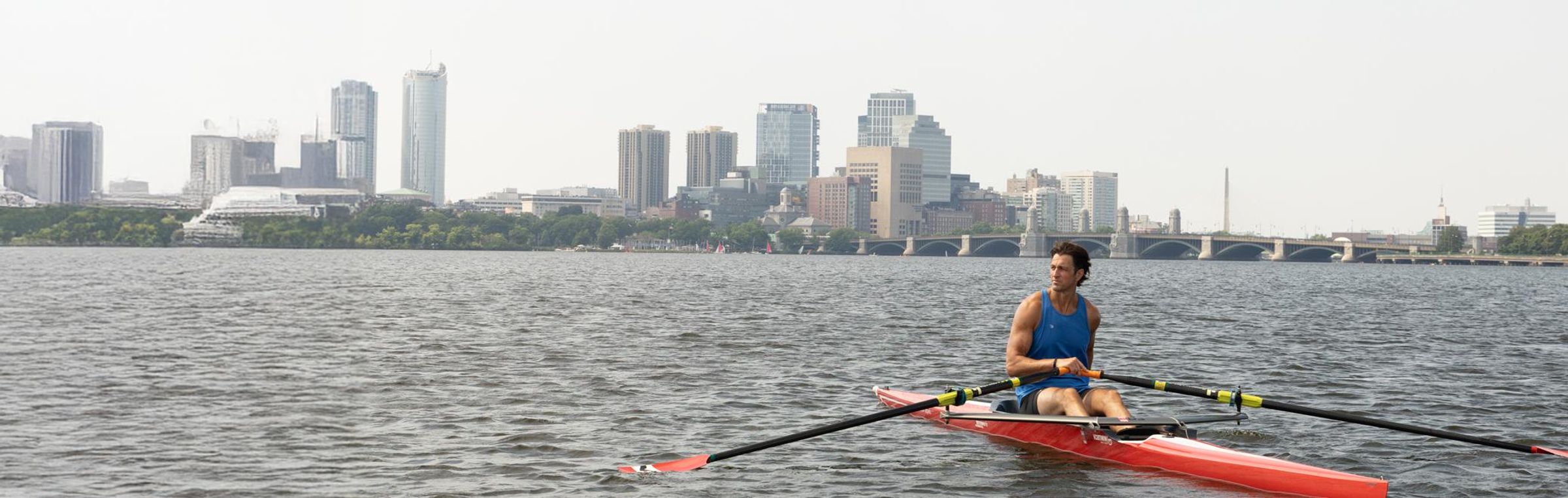 Chris Liwski, rowing a single scull on a lake overlooked by the city.