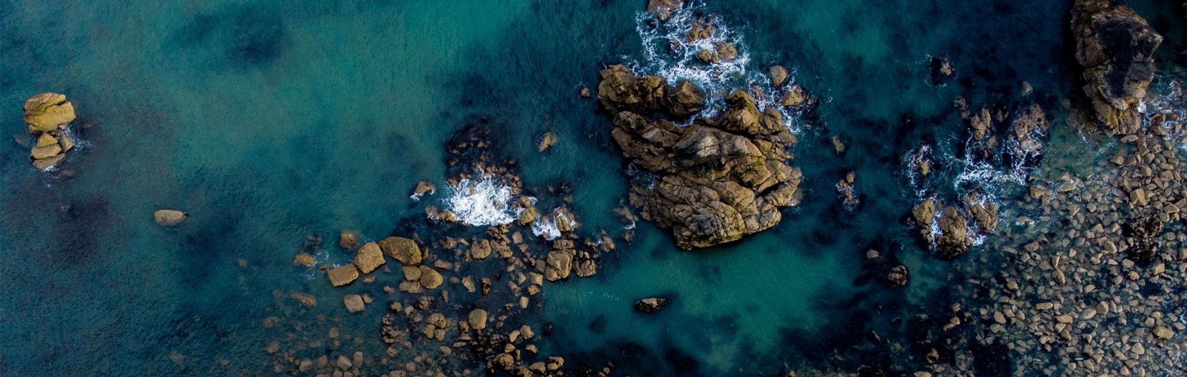 A straight down drone view of Garrarus beach, Waterford Ireland, with sea green waters, coarse sandy beach, and a rocky coast.
