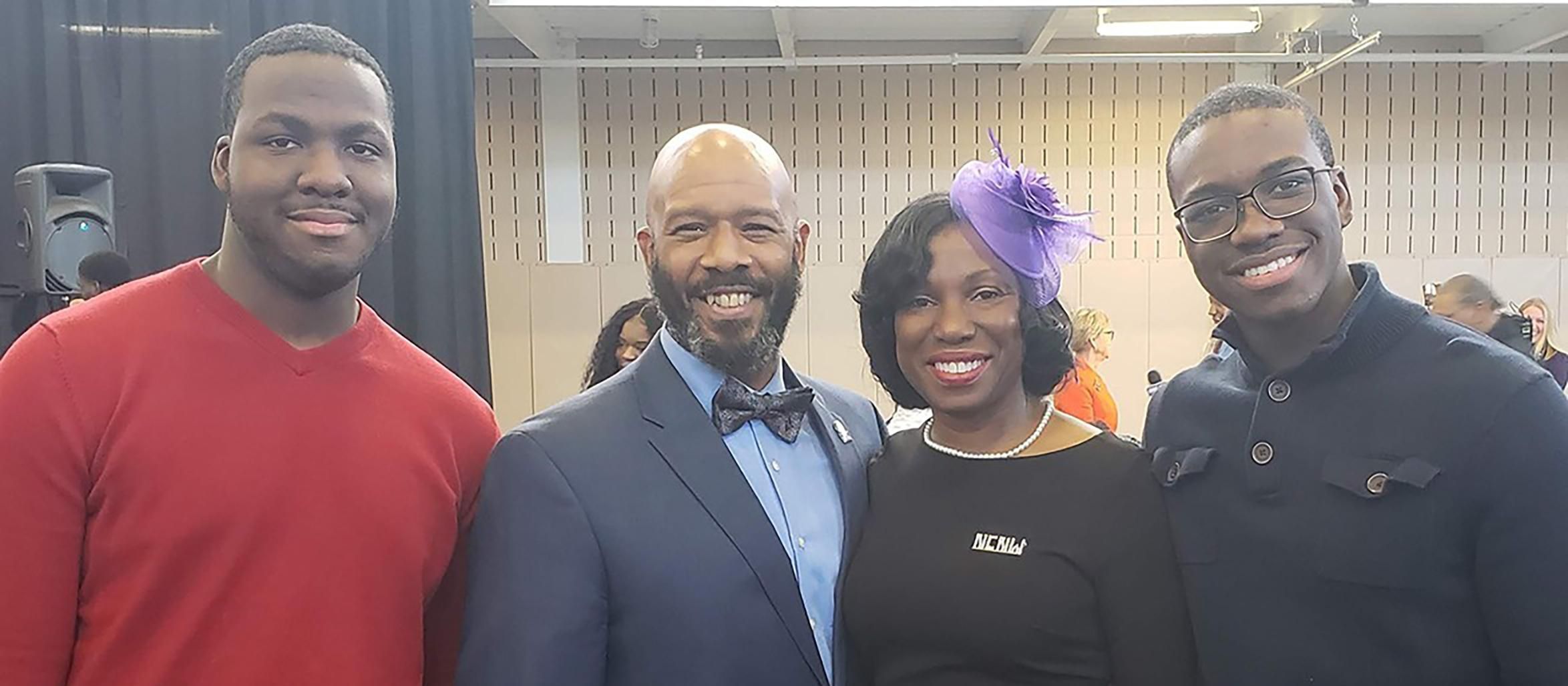 Tameko Patterson, an african american woman, stands with three african american men, all smiling at the camera.