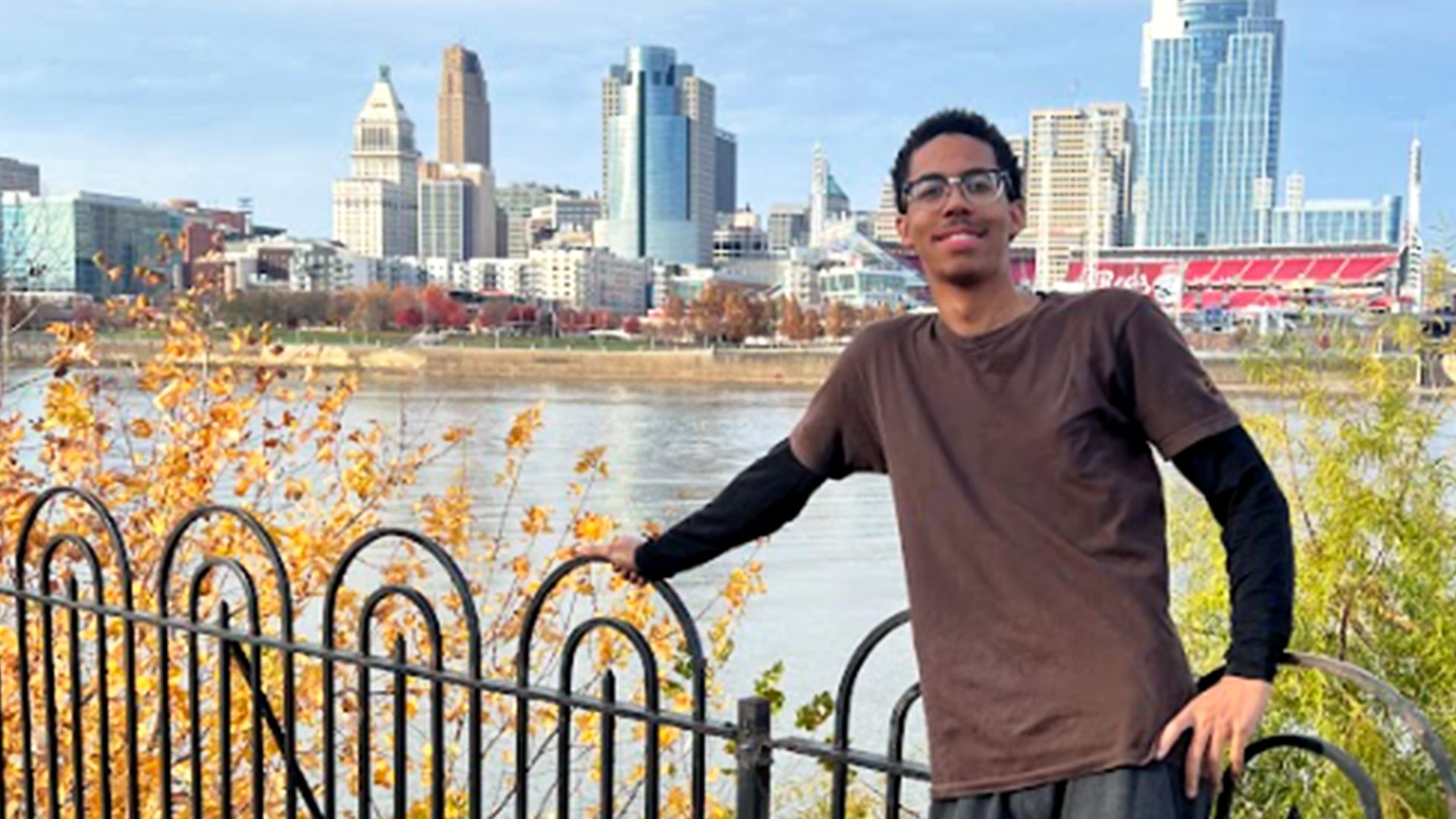 CJ smiling while posing for a picture against the city landscape.
