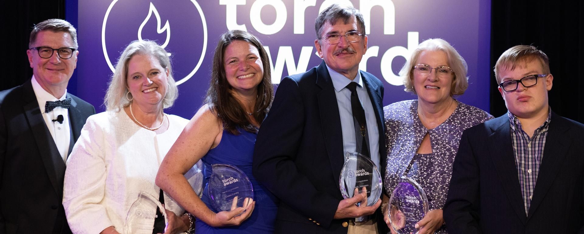 Group shot of the 2023 TORCH award winners holding thier awards made of glass.