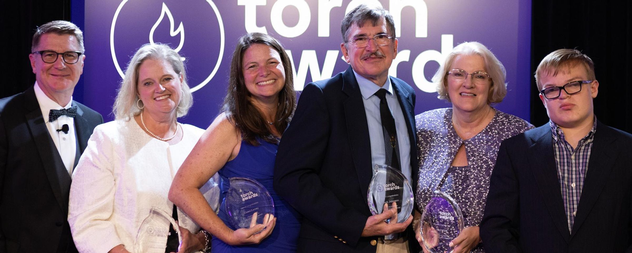 Group shot of the 2023 TORCH award winners holding thier awards made of glass.