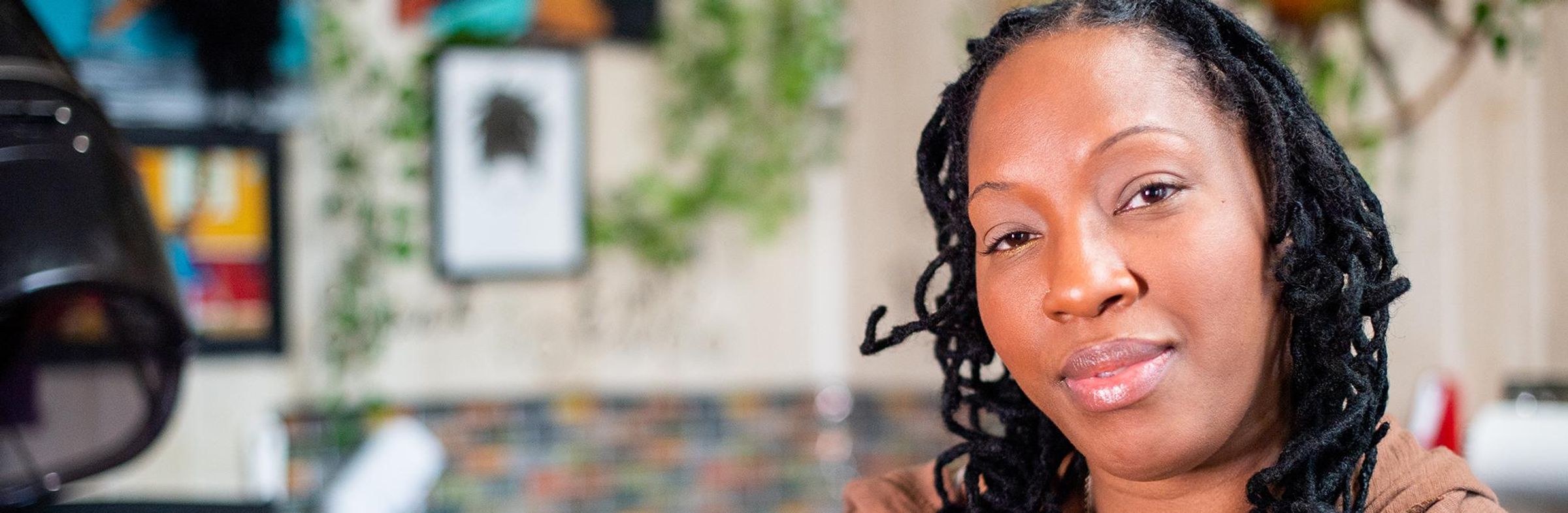A black woman smiles at the camera against the background of her apartment.