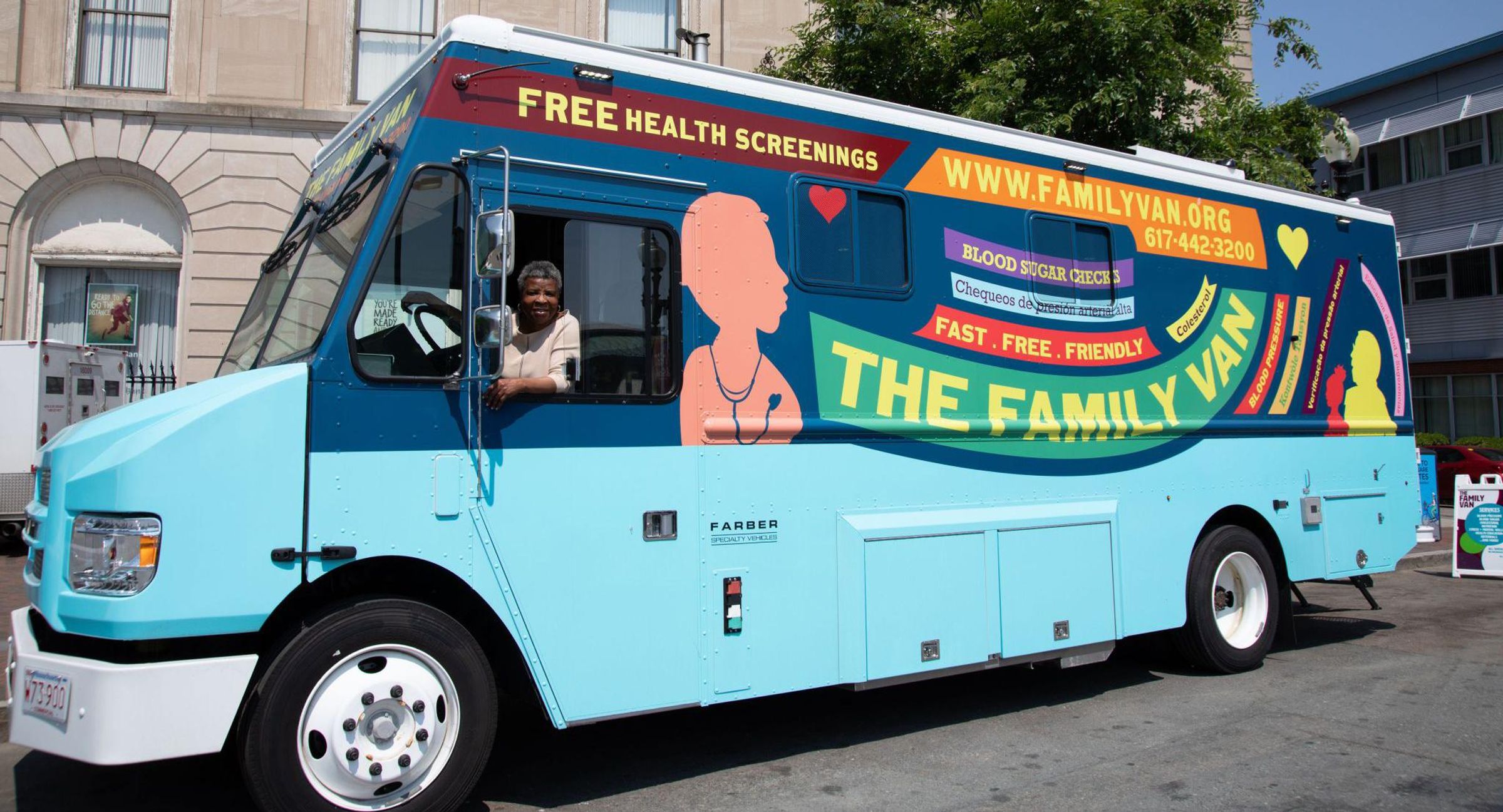 The Family Van mobile health clinic, a bright turquoise van with colorful graphics advertising free health screenings, parked on an urban street with a smiling driver visible through the window.