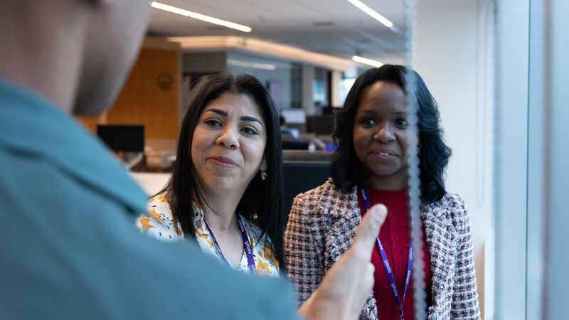Raimunda Rosario, with long black hair and a white shirt with orange flowers, talks with colleagues.