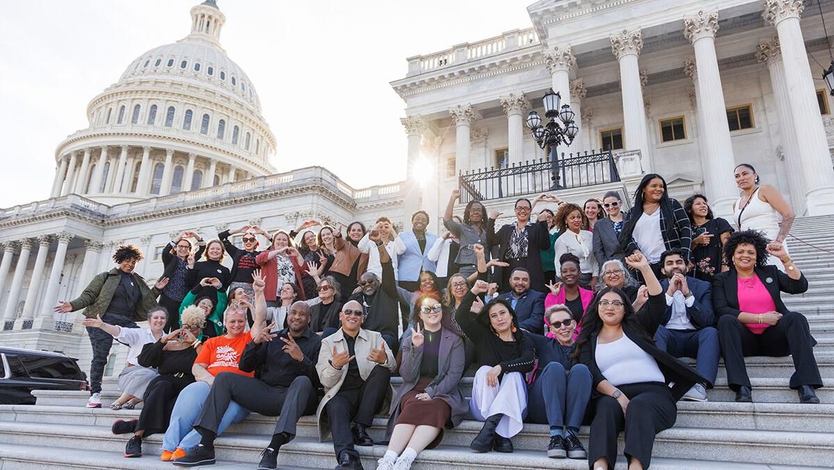 A large group of people sit on the steps of the Capitol in Washington DC